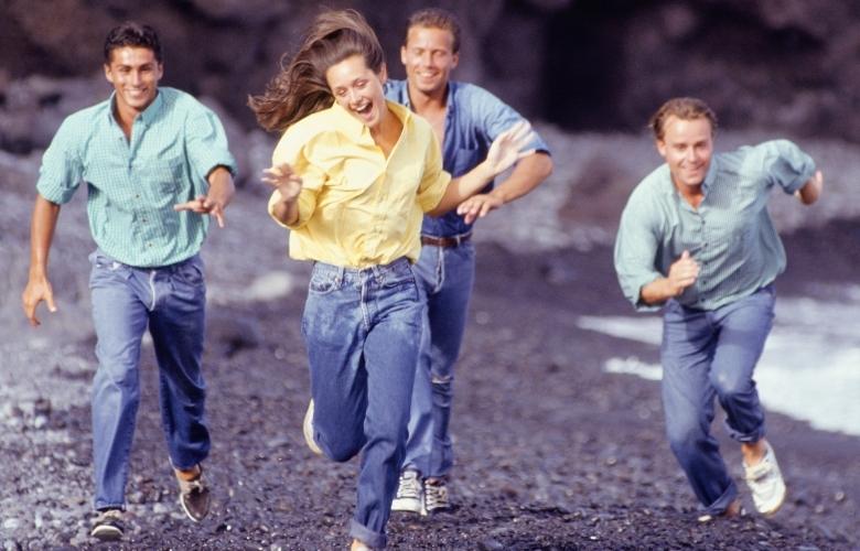 three men are chasing a lady on the beach.