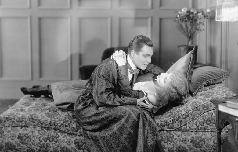 an old photograph of a couple kissing in bed