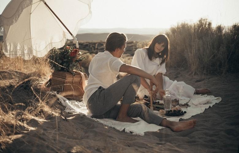 young couple having picnic on sandy beach